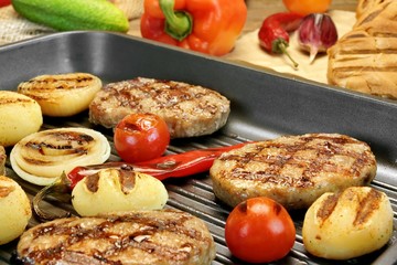 Homemade pan-fried burgers in grill-pan on rustic dinning table.