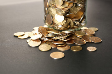 Glass jar with coins on dark background