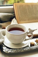 Cup of tea with book on metal tray, closeup
