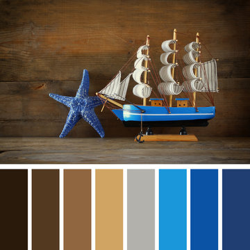 old vintage wooden white sailing boat on wooden table. palette color swatches