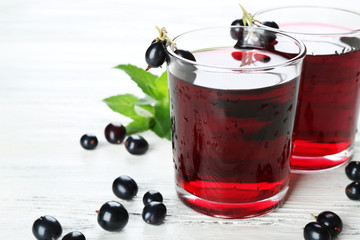 Glasses of fresh blackcurrant juice wooden table background