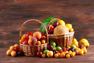 Assorted of fresh fruits in wicker baskets on wooden background