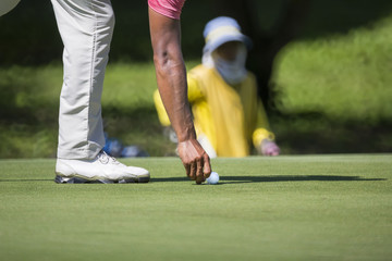 golfer marks his ball  position on a green