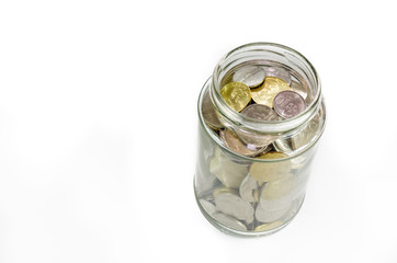 Miniature dream house beside closed glass jar filled with coins isolated on white background.