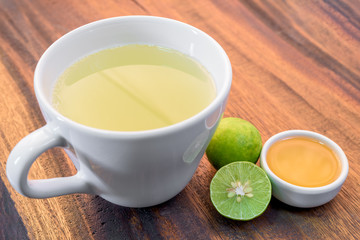 Cup of tea with honey and lemon on wooden table