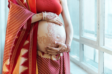 The pregnant woman belly with henna tattoo