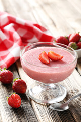 Tasty strawberry mousse in glass on brown wooden table