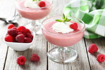 Sweet raspberry mousse in glass on grey wooden table