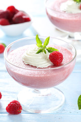 Sweet raspberry mousse in glass on blue wooden table