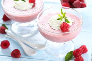 Sweet raspberry mousse in glass on blue wooden table