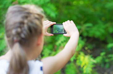 Little girl making video or photo with mobile phone.