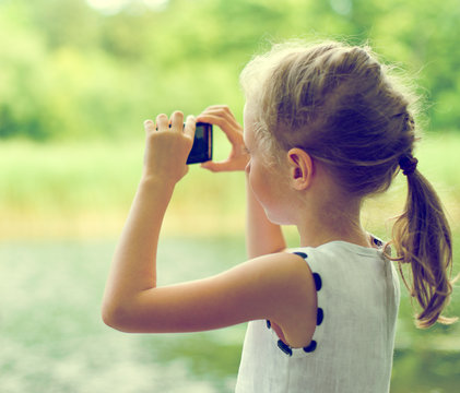 Little girl making video or photo with mobile phone.