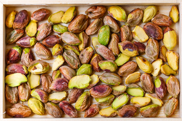 Green pistachio nuts without shell in a wooden box