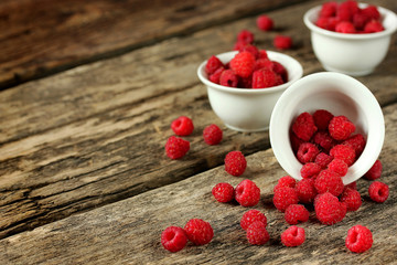 Raspberries in a white bowl on a wooden background
