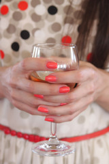 A glass in the hands of the girl - bright manicure