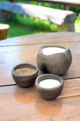 Sugar salt and black milled pepper in brown keramic bawls.