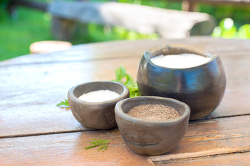 Black milled pepper sugar and salt in brown keramic bawls.