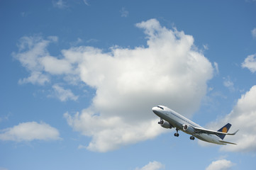 Naklejka na ściany i meble Plane takes off against the blue cloudy sky..