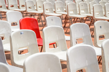 Naklejka premium One red chair surrounded with white chairs