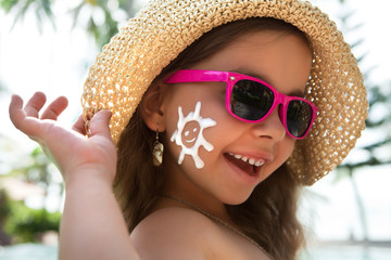 Happy child in glasses with sunscreen on the face