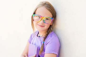 Adorable little girl playing on a digital tablet, wearing rainbow glasses © annanahabed