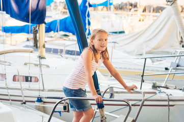 Cute little girl resting on a yacht in a port on a nice summer day