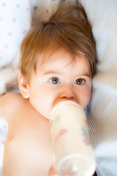 Baby mit gro&szlig;en Augen trinkt Milch aus einer Trinkflasche