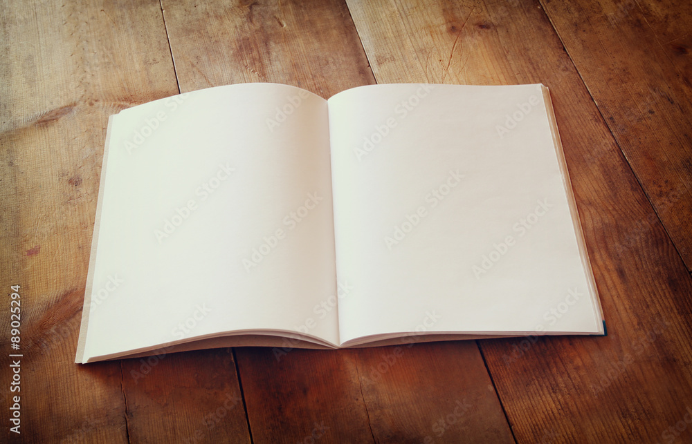 Poster open blank notebook over wooden table. ready for mockup. retro filtered image