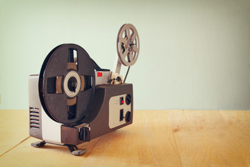 old 8mm Film Projector over wooden table and textured background
