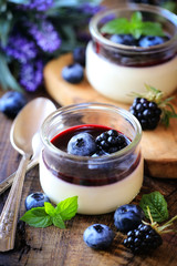 Panna cotta with blueberry and blackberry coulis - Traditional homemade Italian dessert served in...
