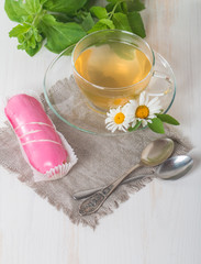 cup of chamomile tea with pink eclair