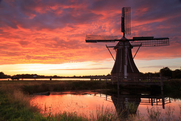 Traditional, Dutch windmill at a pond during a colorful, summer sunset.