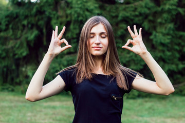 The girl meditates in the fresh air in park.