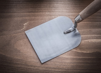 Stainless glazed bricklaying trowel on wooden board construction