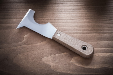 Stainless putty knife on vintage wooden board horizontal version