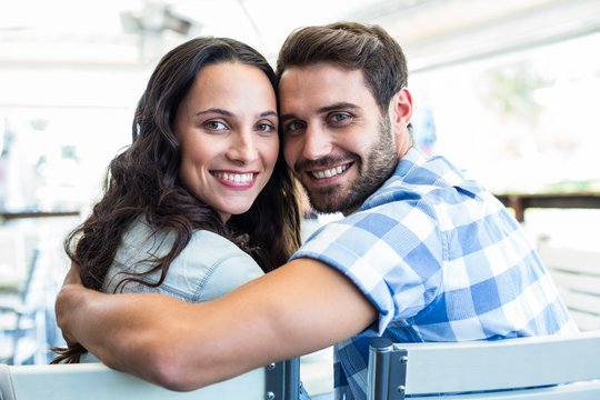 Cute Couple Sitting Outside A Cafe Smiling At Camera