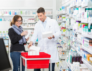Fototapeta na wymiar Male Chemist Showing Medicines To Female Customer
