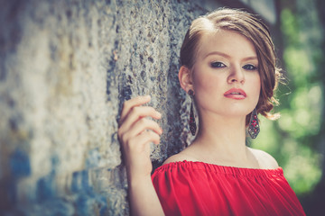 Fototapeta na wymiar portrait of a beautiful young girl in a red dress outdoors