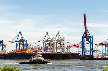 Fototapeta na wymiar Schlepper vor Kränen im Containerhafen