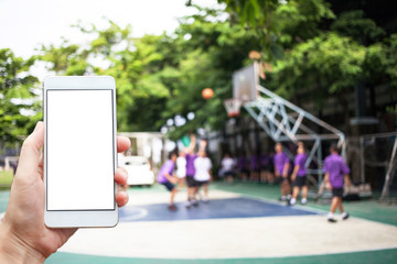 Business conceptual- Focused on left hand holding mobile with Basket ball court blurred background