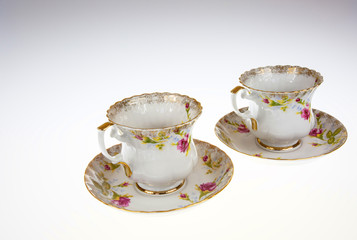 Two porcelain, decorative cups with saucers on isolated white