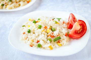 Rice with fried vegetables served with fresh tomato