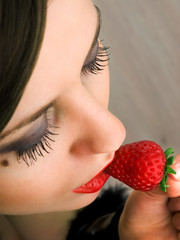 Young woman eating strawberry