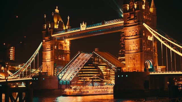 A night close-up of Tower Bridge's lift opening. The Shard and City Hall can be seen in the background. 