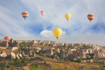 Multi-colored air shata fly over rocks in Cappadocia