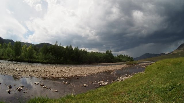 Summer landscape at the riverbank among mountains in overcast day. Fisheye. Timelapse