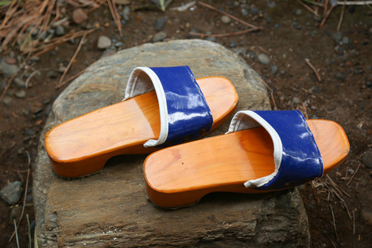 Traditional Japanese Zen Wooden Shoes on a Rock in a Garden.