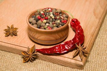 The grains of pepper, cilli and star anise on a wooden surface