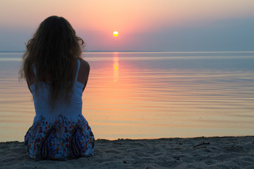Girl at the sea at sunset
