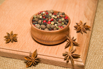 The grains of pepper and star anise on a wooden surface